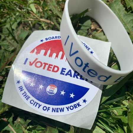 an I Voted Early sticker and an I Voted bracelet in grass
